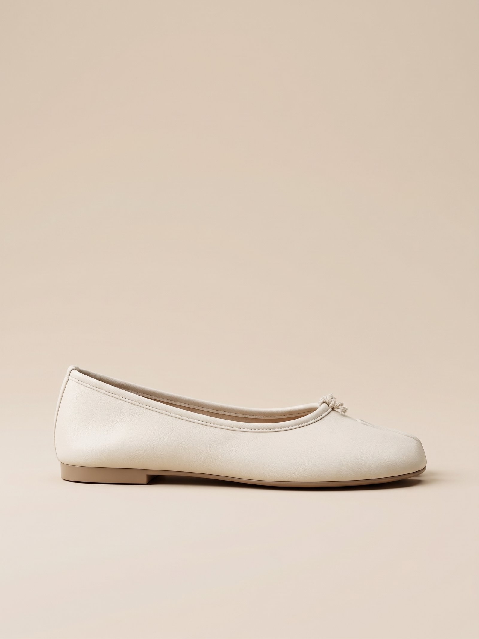 Profil de la ballerine plate Tabi pour femme, montrant la ligne épurée et la souplesse du simili cuir blanc cassé.